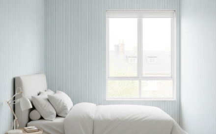 Dormitorio pequeño con papel tapiz de rayas verticales en tonos pastel que da sensación de mayor altura
