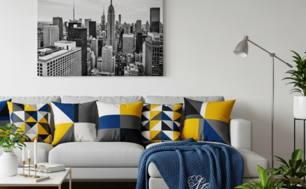 Salón moderno con decoración personalizada, incluyendo cojines con patrones geométricos, una manta personalizada y un cuadro en la pared.